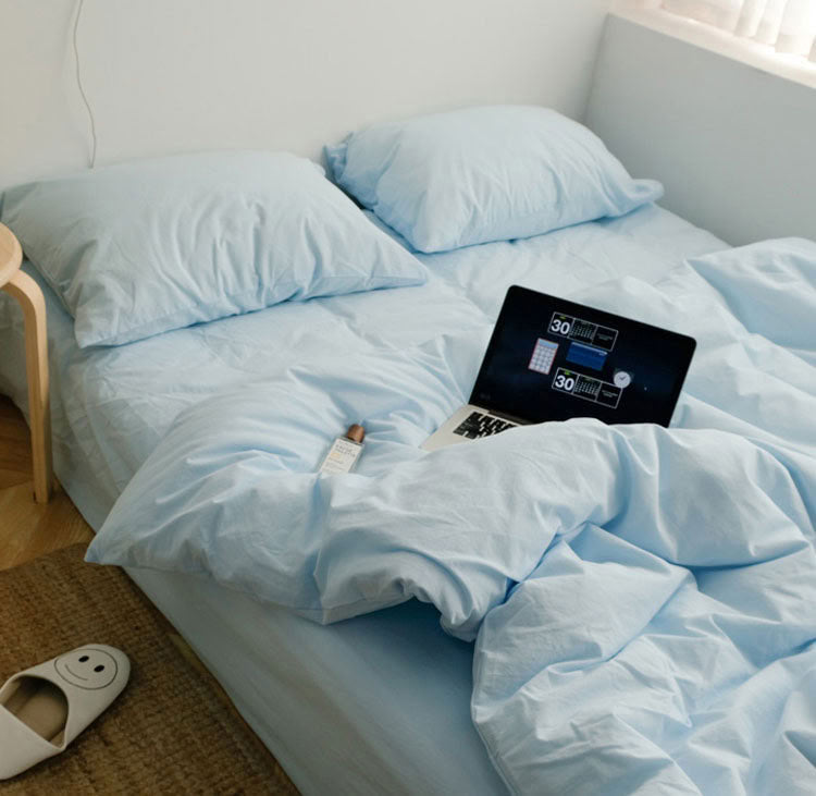 Soft sky blue washed cotton bedding set in a bright minimalist bedroom with wooden floor - RoomDen