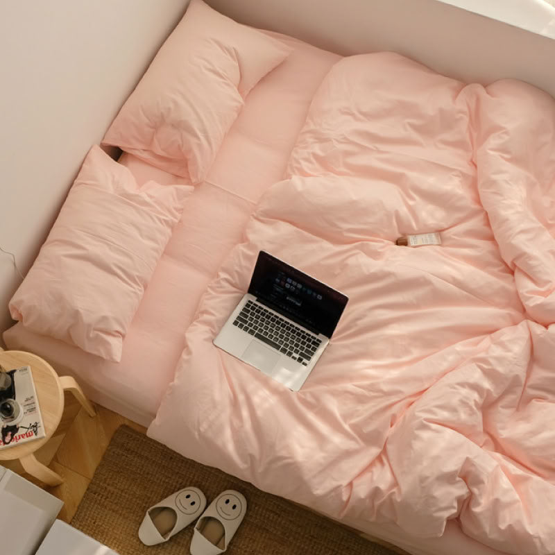 Rose pink washed cotton bedding set with matching pillows and laptop on the bed - RoomDen