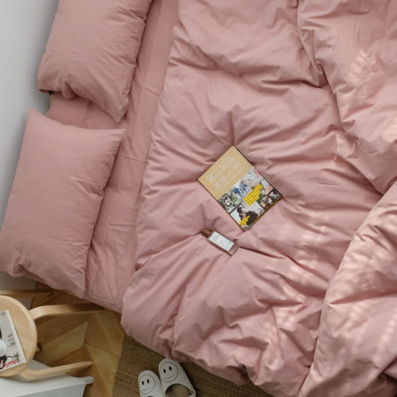 Soft blush pink washed cotton bedding set in a cozy minimalist bedroom with natural sunlight - RoomDen