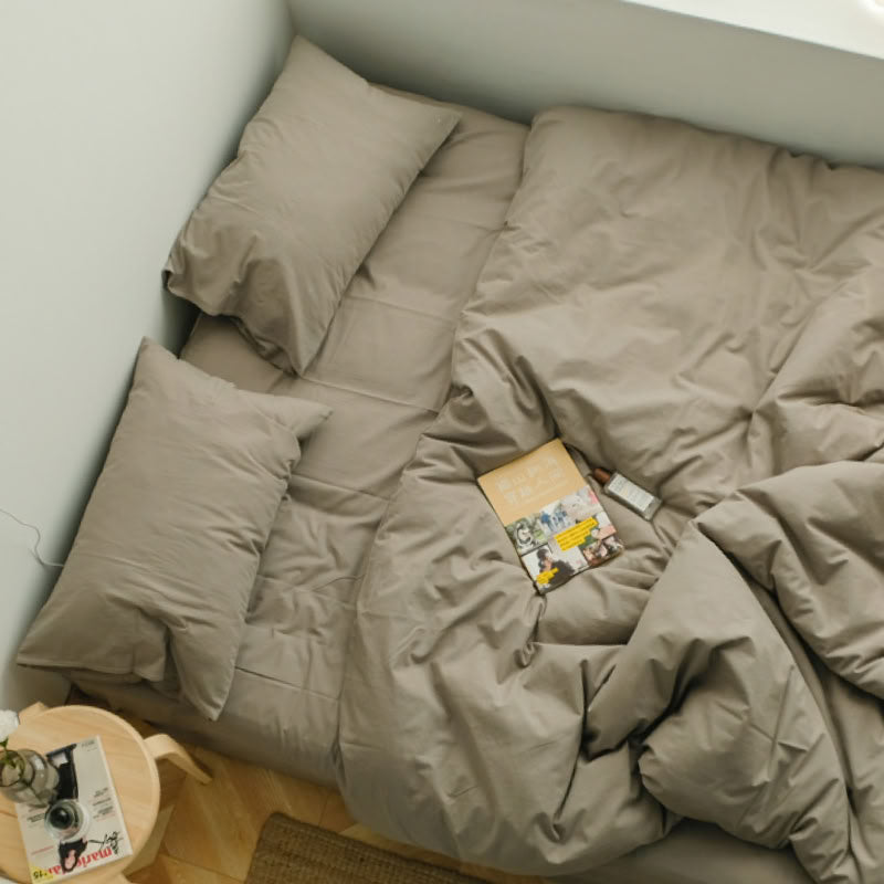 Soft olive green washed cotton bedding set with a book and sunlight on the bed - RoomDen