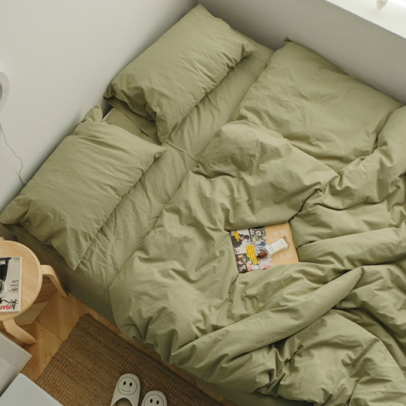Soft Pistachio Green washed cotton bedding set with a book and warm natural light - RoomDen