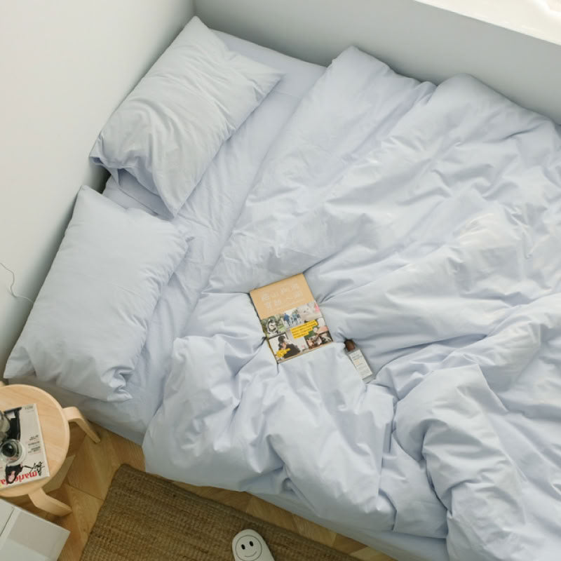 Cozy light blue washed cotton bedding set with a book and slippers, perfect for a slow morning - RoomDen