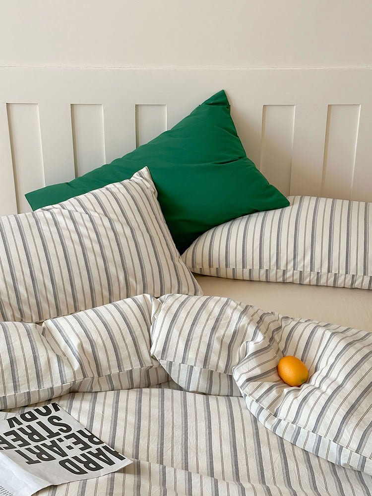 Grey striped washed cotton bedding set with striped and solid pillowcases on wooden bed – RoomDen