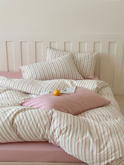 Pink striped washed cotton bedding set with striped and solid pillowcases on wooden bed – RoomDen