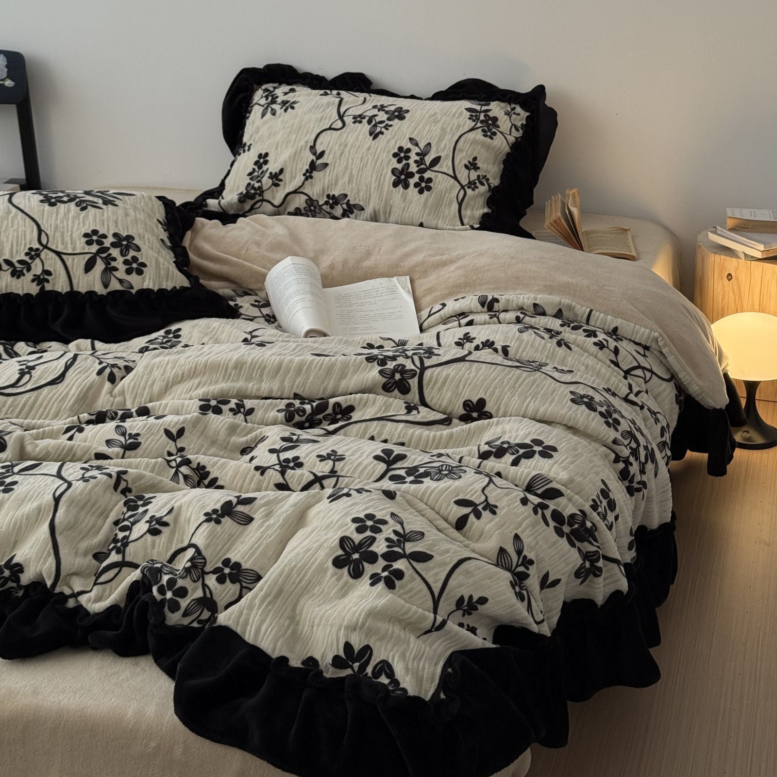 RoomDen textured cream bedding with black floral patterns and ruffle trim, side view.