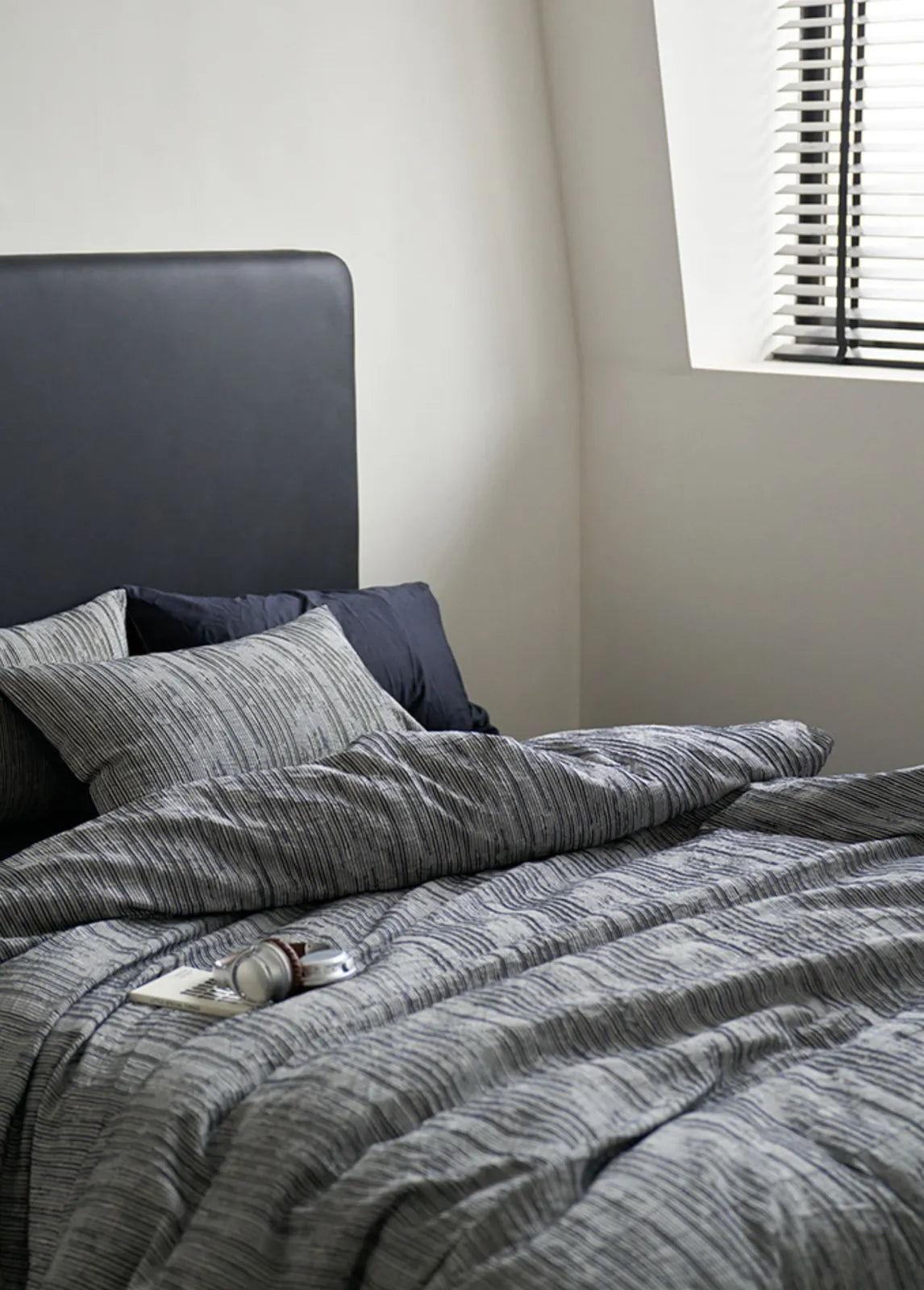 Dark grey headboard styled with beige striped washed cotton bedding RoomDen.