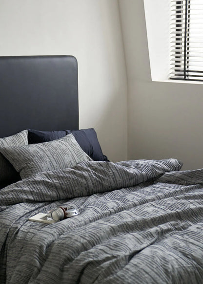 Dark grey headboard styled with beige striped washed cotton bedding RoomDen.