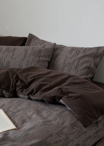 Side view of dark grey bedding set showing reversible solid back color RoomDen.