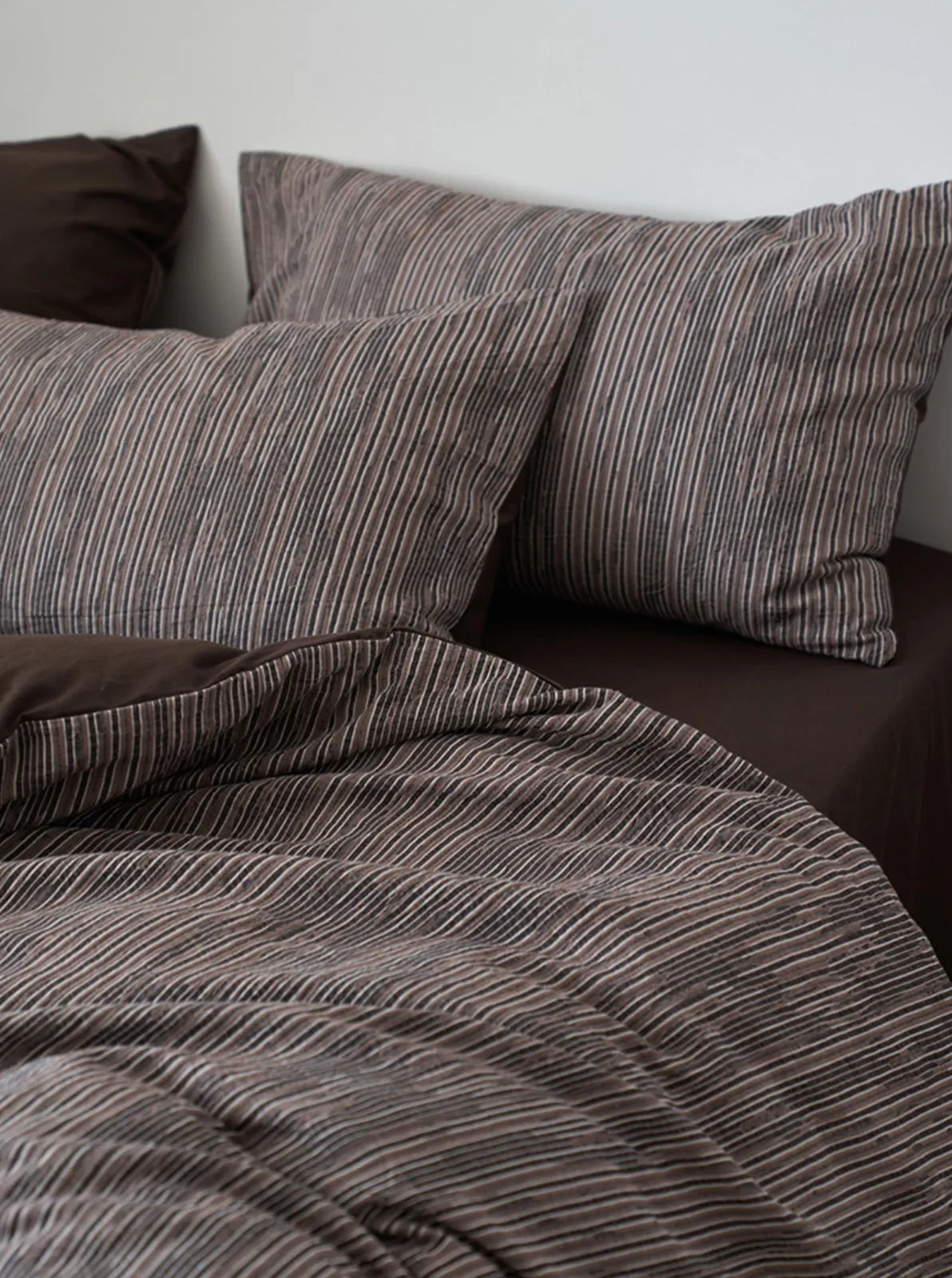 Overhead shot of charcoal grey striped pillows and duvet texture RoomDen.