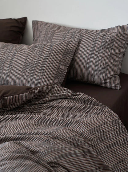 Overhead shot of charcoal grey striped pillows and duvet texture RoomDen.