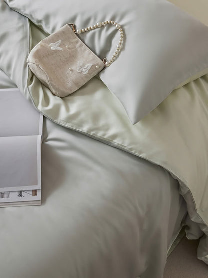 Close-up of mint green Tencel duvet and pillow with pearl bag accent on the bed – RoomDen