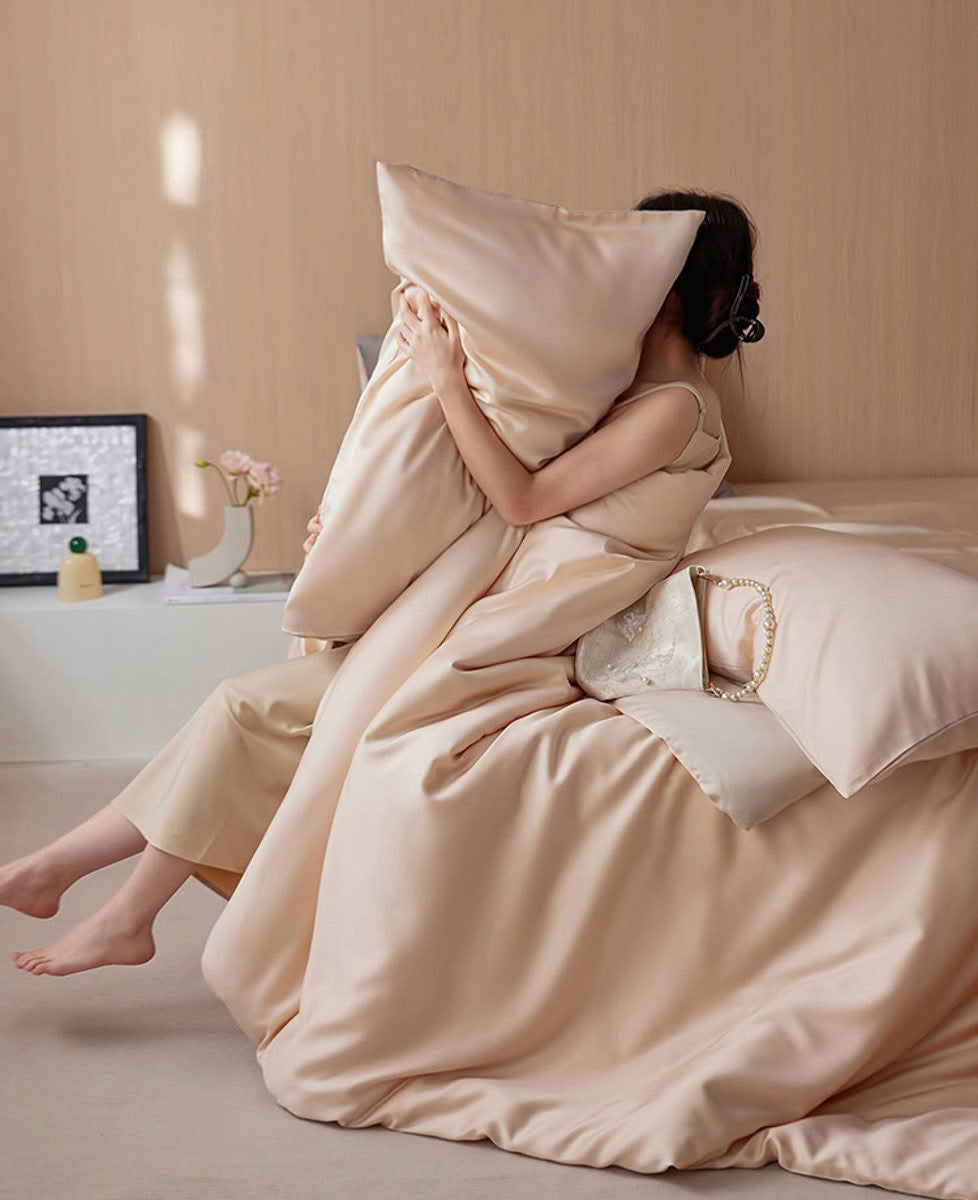 Woman embracing beige-pink silky pillow and duvet in minimalist bedroom – RoomDen