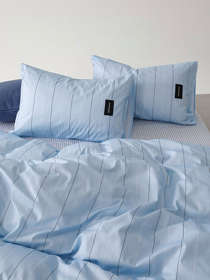  Pillowcase detail showing black woven label on light blue pinstripe fabric – RoomDen