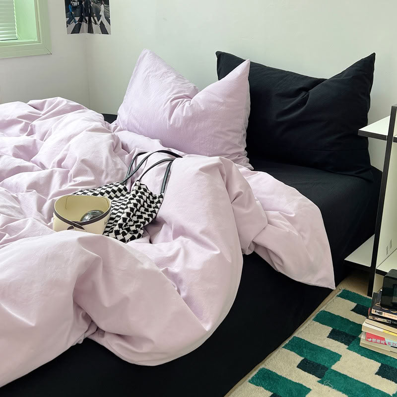 Soft lavender and black bedding styled with magazine and candle decor – RoomDen