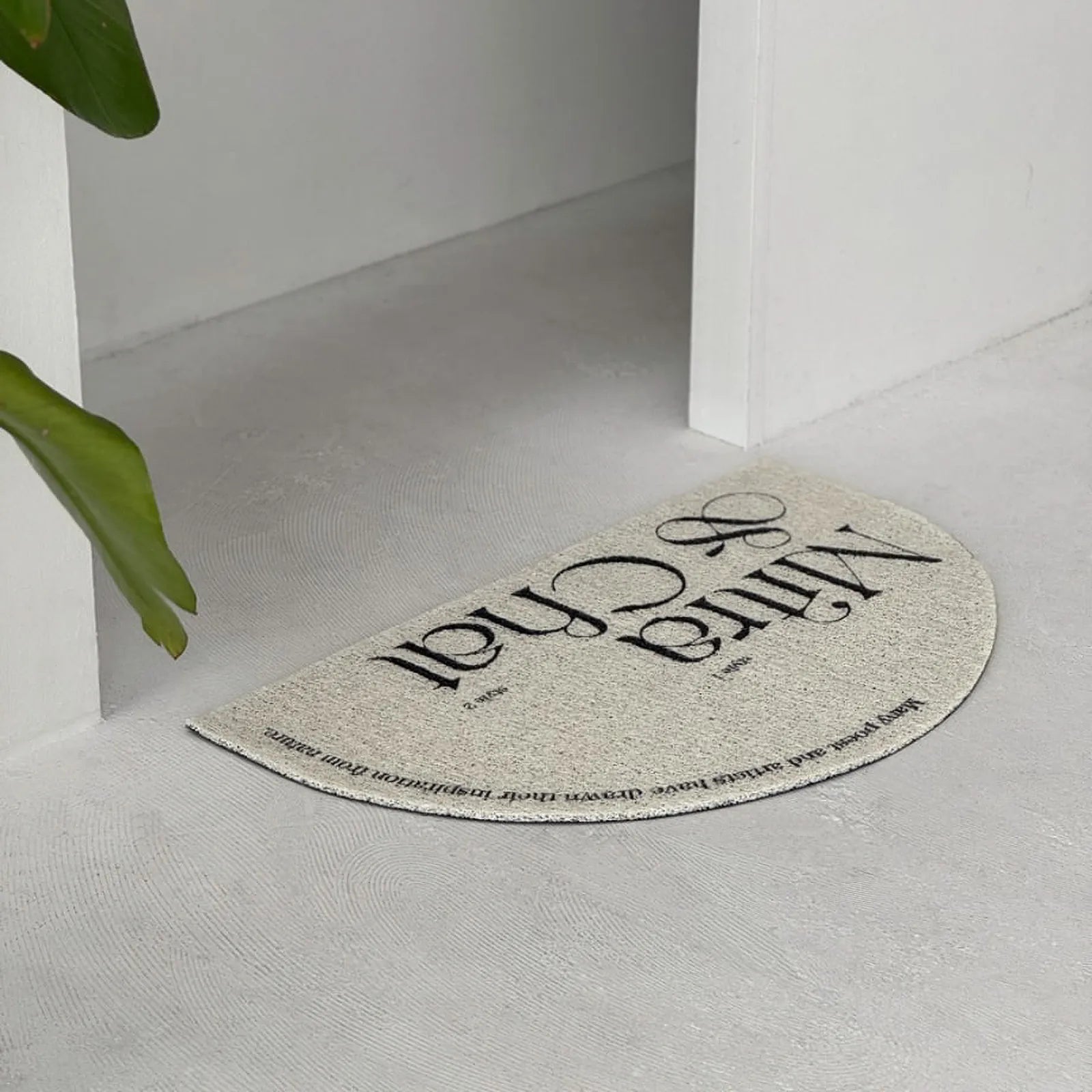 RoomDen cream semi-circle doormat placed in a white minimalist entryway.