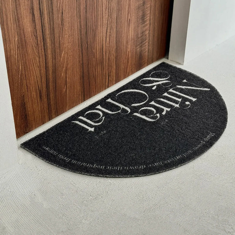 Black half-moon PVC coil rug placed against a raw wooden door - RoomDen