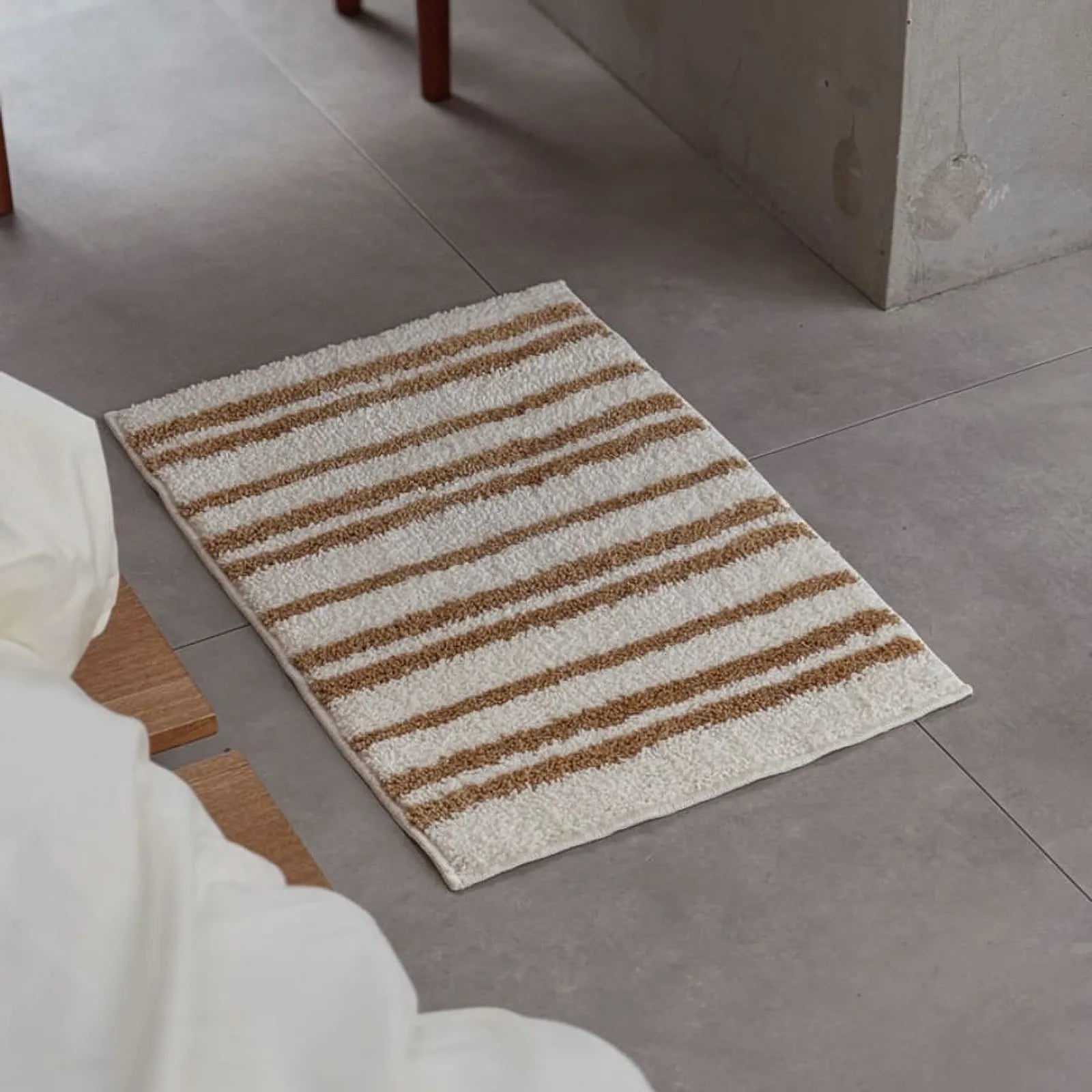 High-angle view of caramel and cream striped shaggy rug on grey tile floor - RoomDen