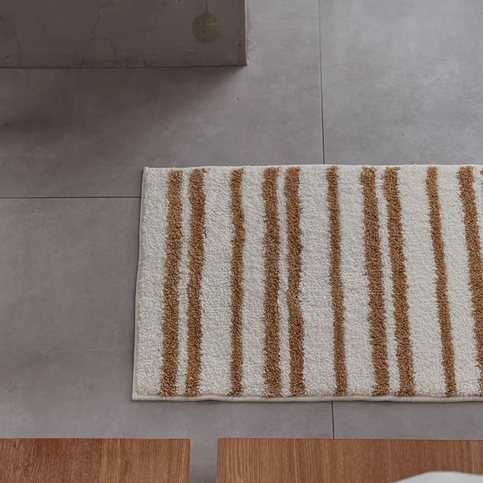 Top-down view of the rectangular striped bath mat on a tiled bathroom floor - RoomDen