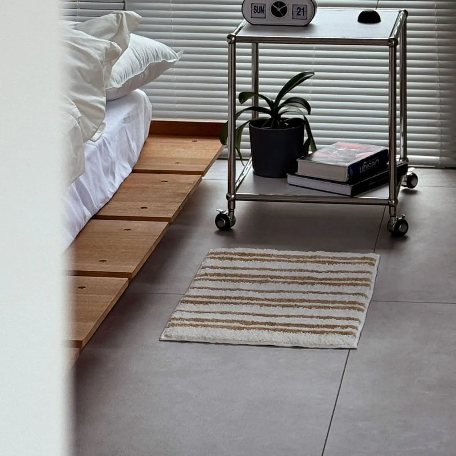 Bedroom scene with the striped rug placed next to a metal bedside table - RoomDen