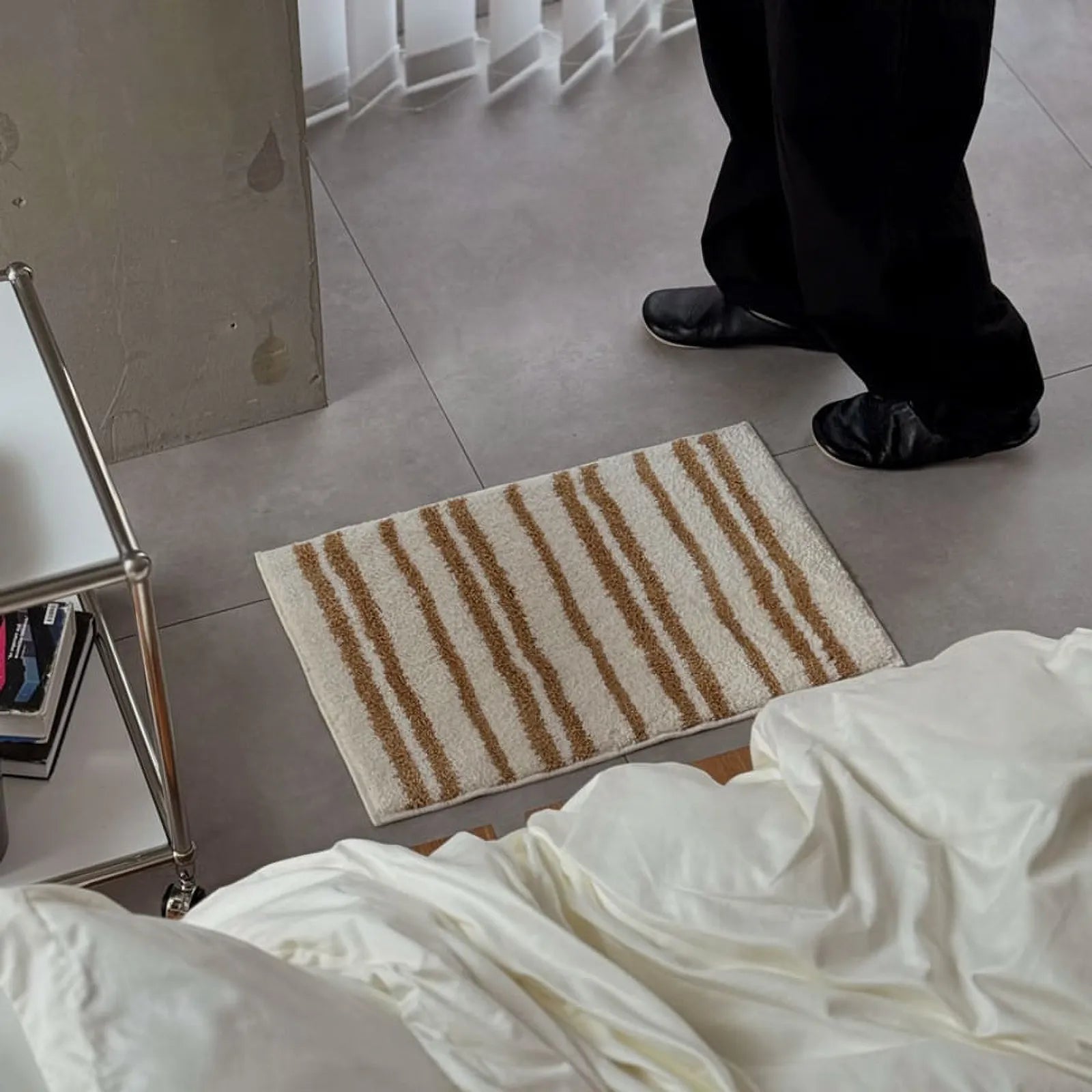 Person standing on the striped rug in black pants, showing scale - RoomDen