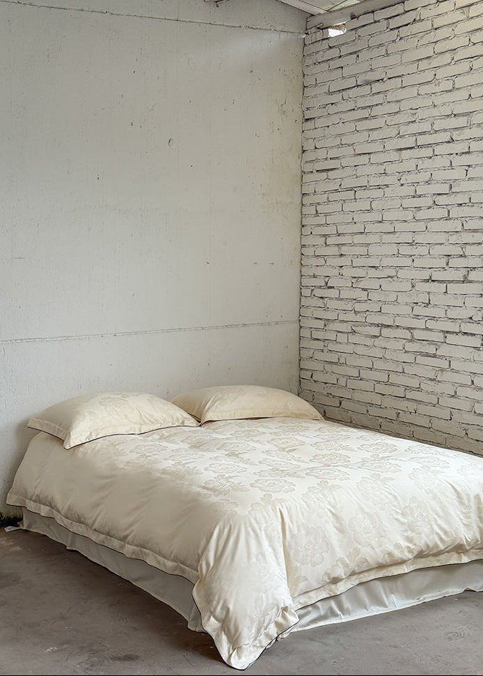 Ondine Floral Cotton Blend Bedding Set – full ivory floral bed against a white brick wall - Roomden