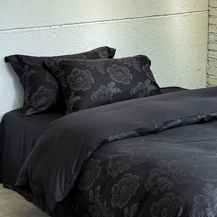 Ondine Floral Cotton Blend Bedding Set – folded black duvet with matching floral pillows behind it - Roomden
