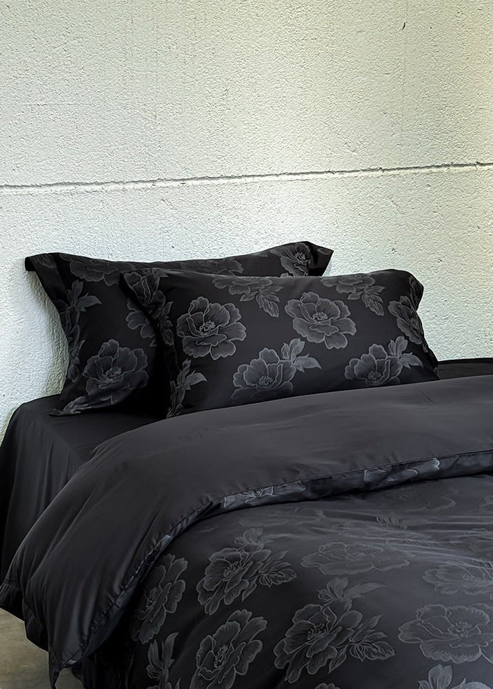 Ondine Floral Cotton Blend Bedding Set – black floral pillows above a turned-back plain duvet reverse - Roomden