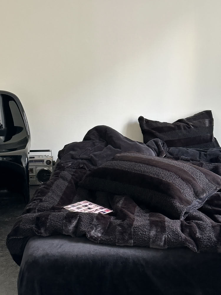Black wide striped plush fleece bedding set styled in a minimalist room with modern decor and cozy texture - RoomDen