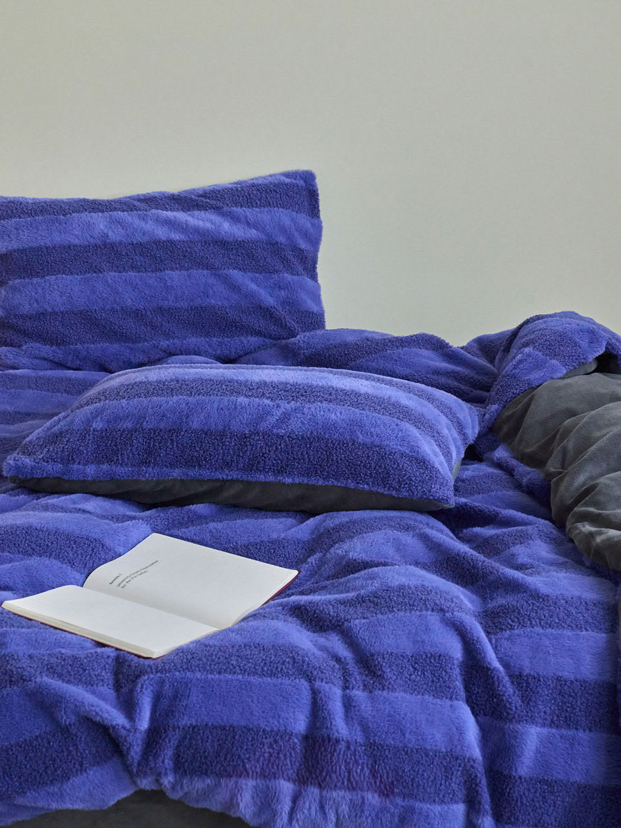 Blue striped plush fleece bedding set on minimalist bed setup creating cozy winter atmosphere - RoomDen