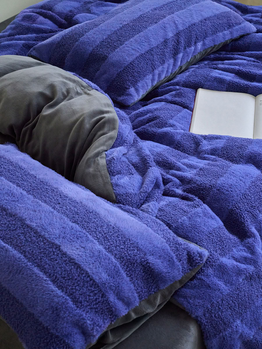 Close-up of blue plush fleece bedding showing fluffy thick texture and soft cozy stripes - RoomDen